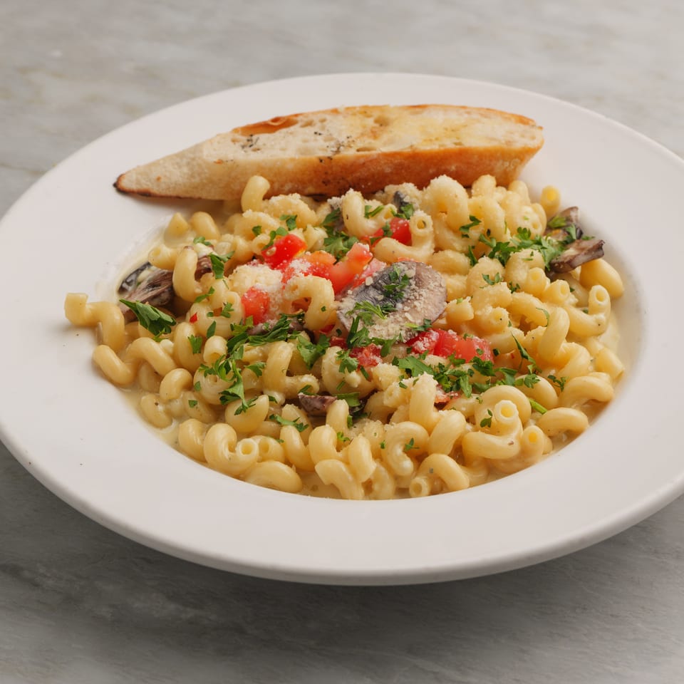 Creamy pasta with mushrooms, diced tomatoes, parsley, and grated cheese, served with garlic bread.