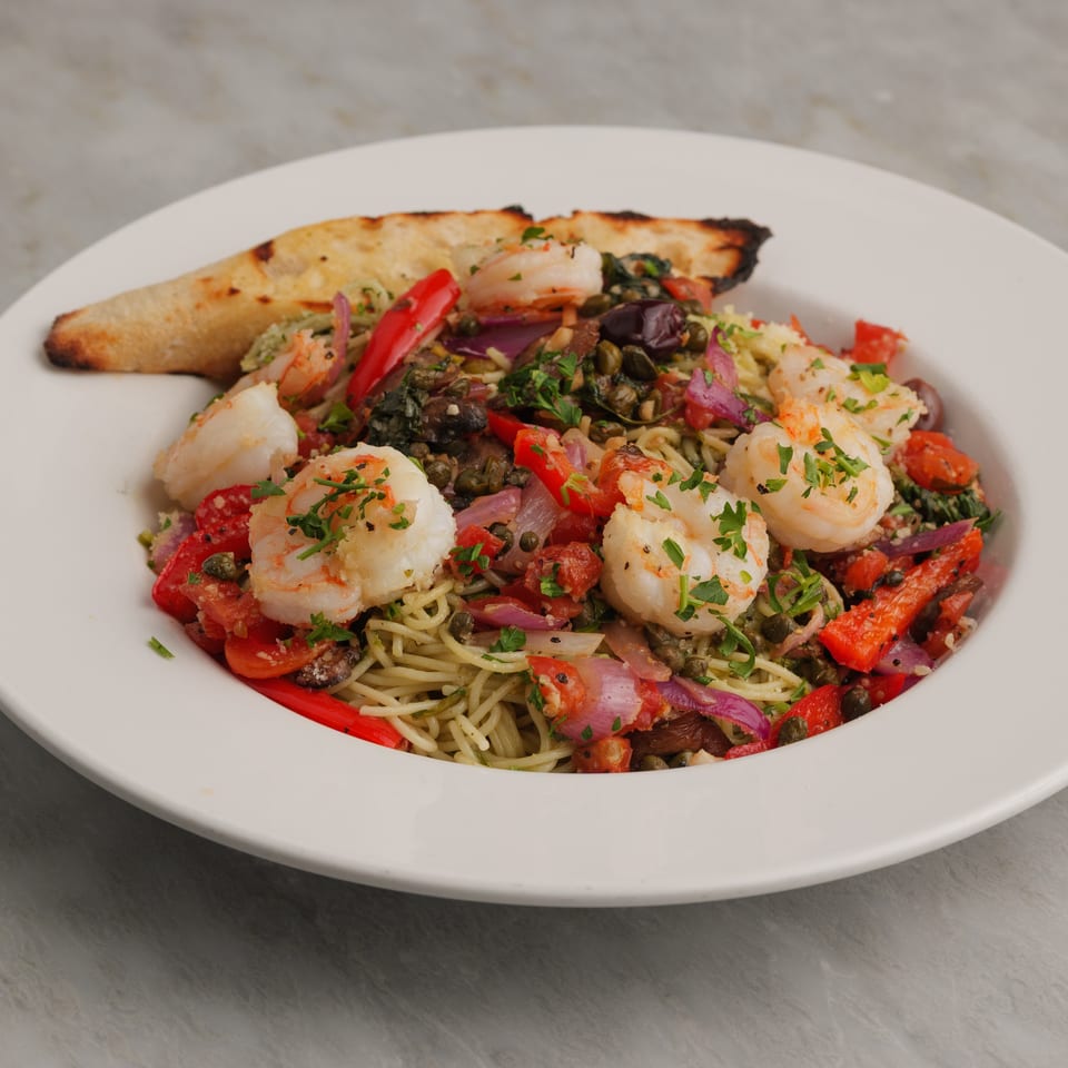Shrimp scampi pasta with red peppers, onions, capers, and a side of toasted bread.